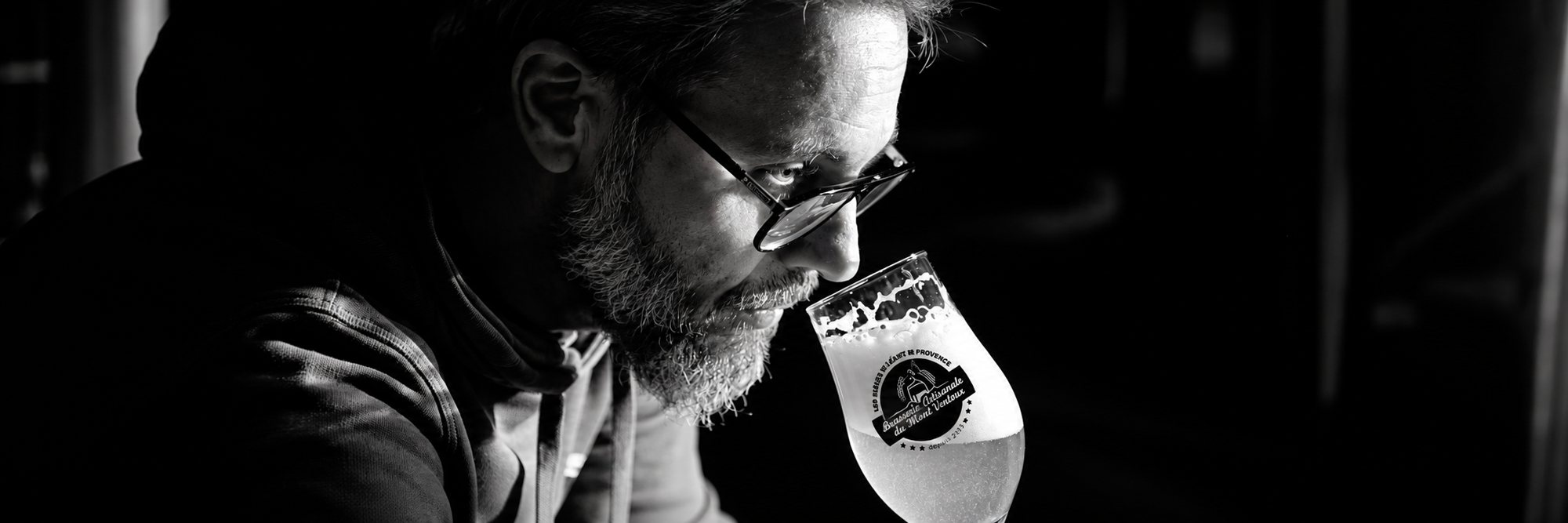 Un brasseur barbu hume un verre de bière, photo en noir et blanc