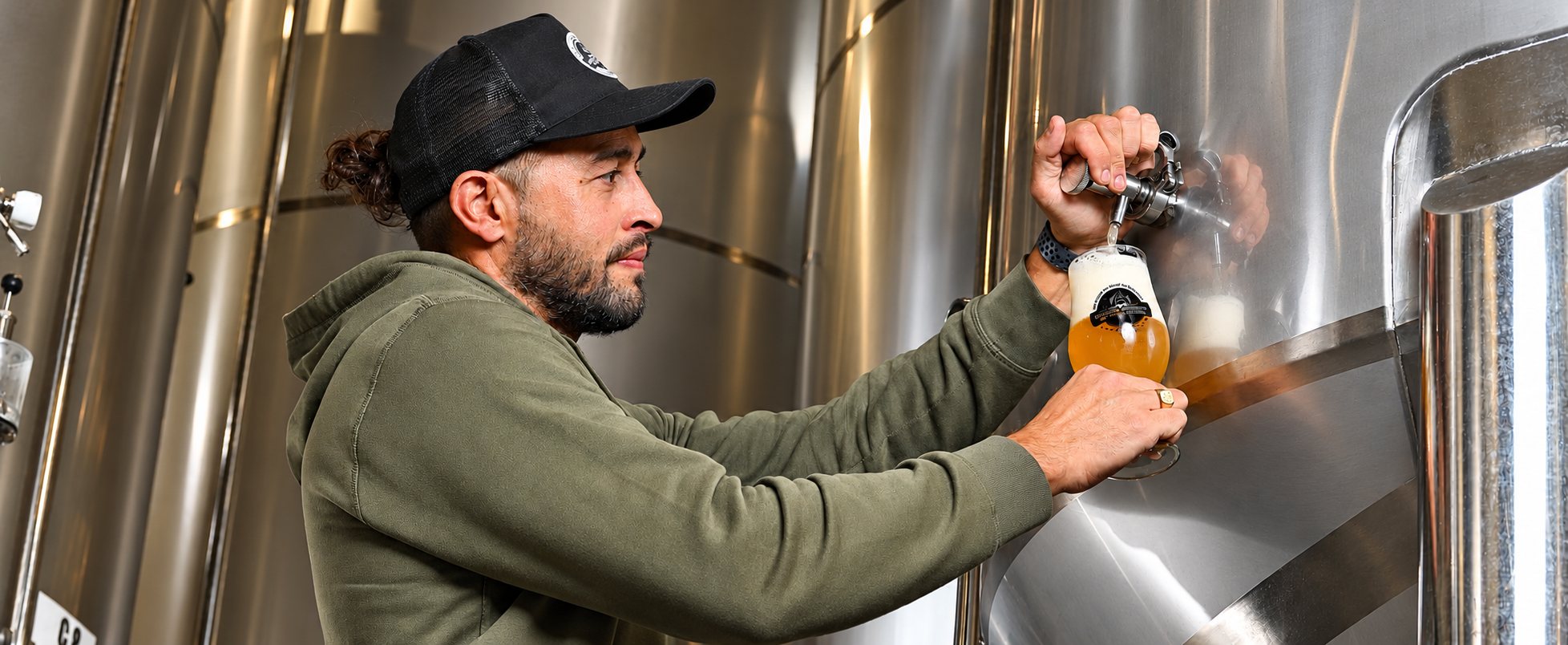 Un brasseur sert une bière blonde devant une cuve en inox
