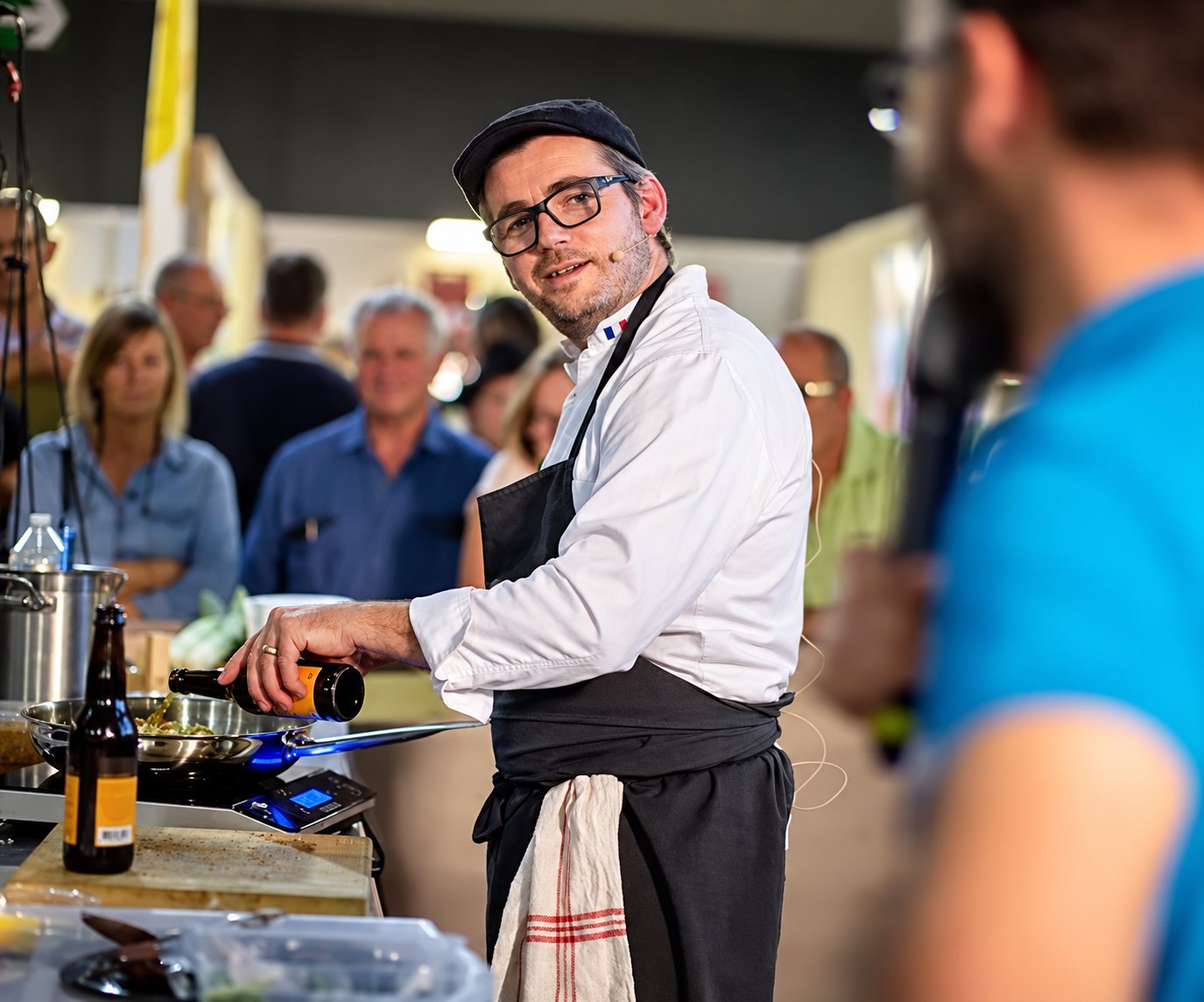 Un chef cuisine devant un public lors d’une démonstration culinaire