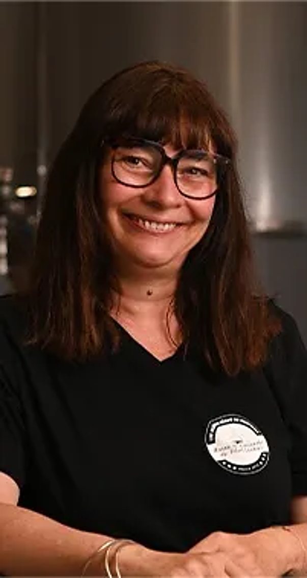 Corinne, souriante, avec des lunettes et un t-shirt noir