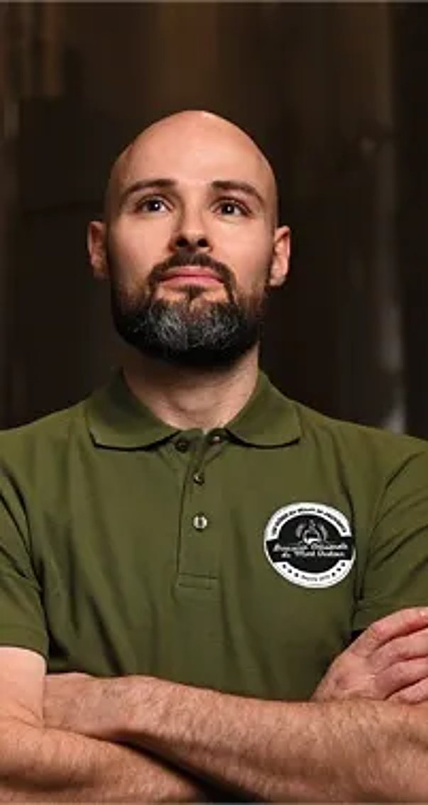 Pierre-Emmanuel, barbu, en polo vert, les bras croisés